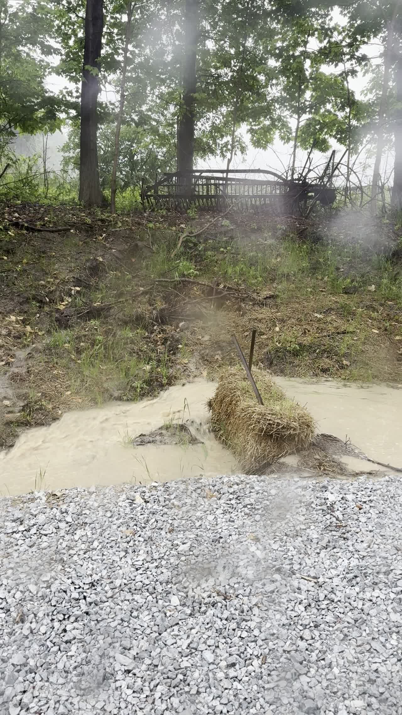 Muddy runoff flowing around an overwhelmed straw-bale filter